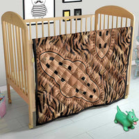Beige tribal pattern quilt draped across a wooden baby bed