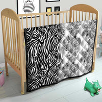 Black-and-white quilt laid in a crib, zebra stripe left and paisley print right.
