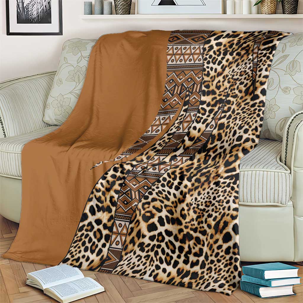 Leopard print and tribal stripe blanket with tan solid side, laid over a sofa arm.