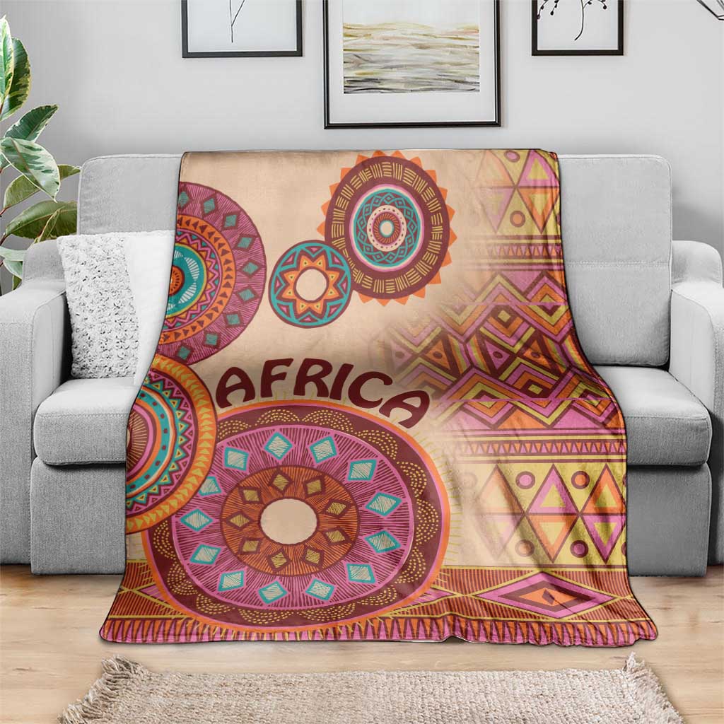 Beige throw blanket with 'AFRICA' lettering and colorful circular mandala motifs, geometric border