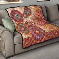 Beige throw quilt on sofa with 'Africa' lettering and multicolor tribal circular designs