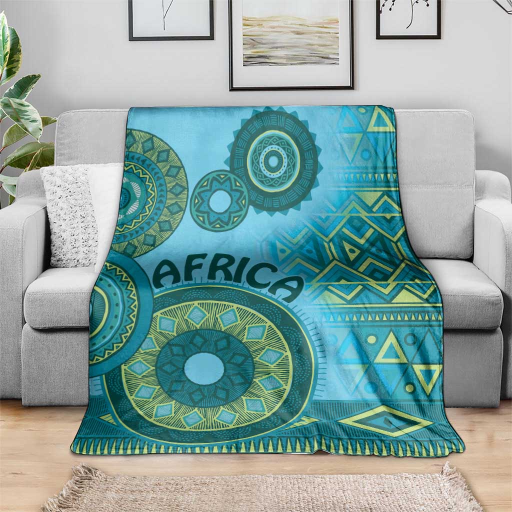 Blue tribal throw blanket with teal flower-like circles, geometric stripes, and tassel fringe