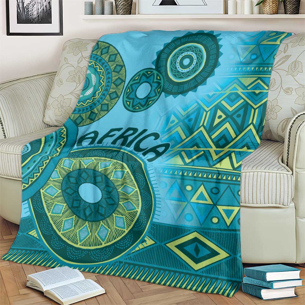 Blue tribal blanket draped over sofa with teal circular motifs, zigzags, and diamond shapes