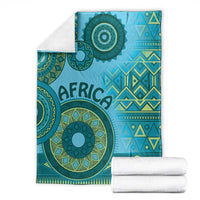 Blue tribal blanket with teal circular design, folds, and matching white fabric rolls