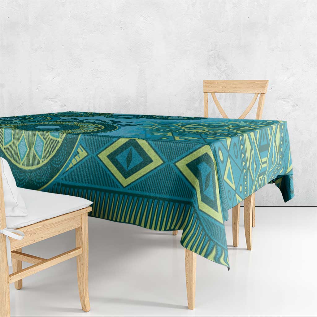 Blue and teal geometric motif tablecloth draped over dining table, fringed edge