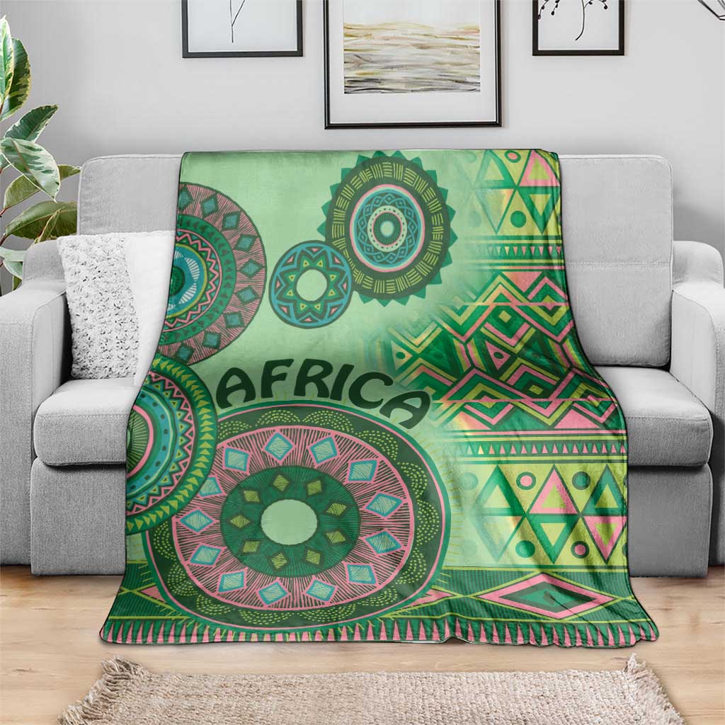 Green tribal pattern blanket draped over a couch, with mandala circles and diamond stripes