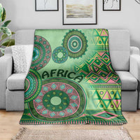 Green tribal pattern blanket draped over a couch, with mandala circles and diamond stripes