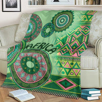 Green tribal pattern blanket on a sofa with bold mandala medallion and zigzag designs