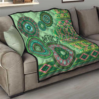 Green tribal pattern throw quilt with circular emblems, pink geometric diamonds, and dark trim