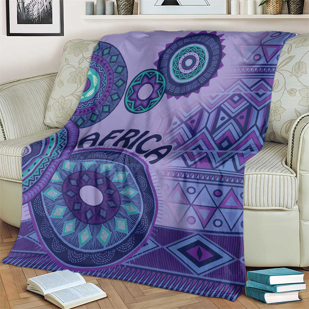 Purple tribal geometric blanket on sofa with large circular emblem and fringe edge