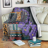 Dark blanket with purple blossoms and colorful tribal blocks over couch and armrest