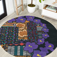 Round carpet with violet flower appliques and multicolor tribal geometric pattern on dark base