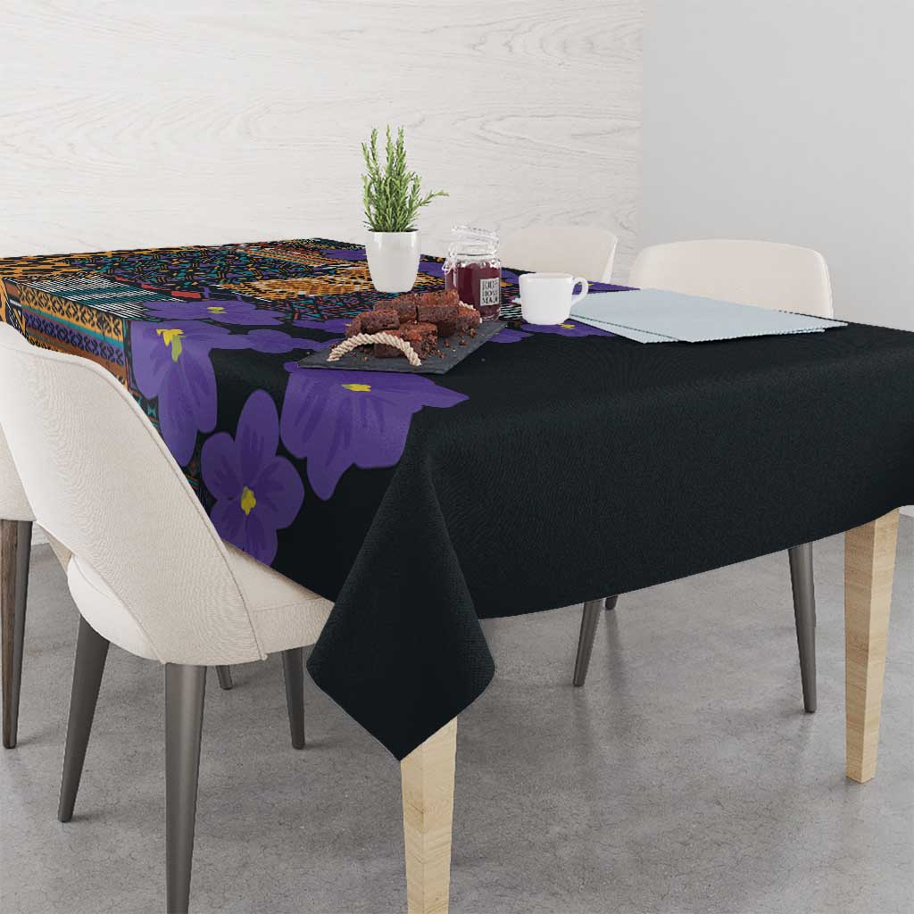 Black tablecloth with purple-violet flower print and colorful tribal motif across top.