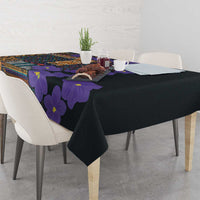 Black tablecloth with purple-violet flower print and colorful tribal motif across top.