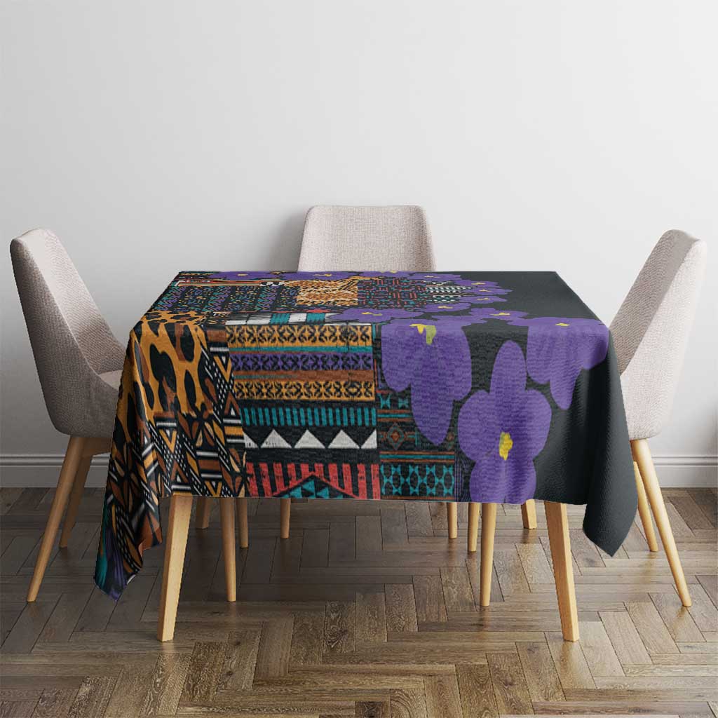 Tablecloth on a dining set: black base with violet flowers and multicolor geometric bands.