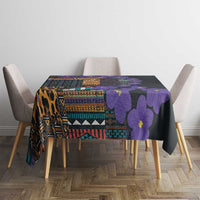 Tablecloth on a dining set: black base with violet flowers and multicolor geometric bands.