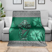 Green Celtic blanket draped on sofa, harp and shamrock motifs with black-and-white trim