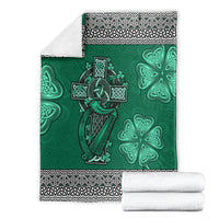 Green Celtic cross and harp blanket with shamrock motifs, folded with black-and-white border