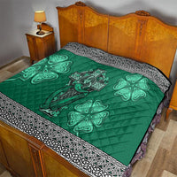 Green quilt laid on a bed with Celtic cross, harp and shamrock graphics and black-and-white border.