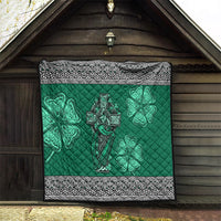 Green quilt hung on wooden wall showing Celtic cross and harp centerpiece with shamrock clovers.