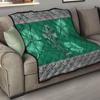 Green quilt draped over sofa arm with Celtic cross and harp center and shamrock clover decorations.