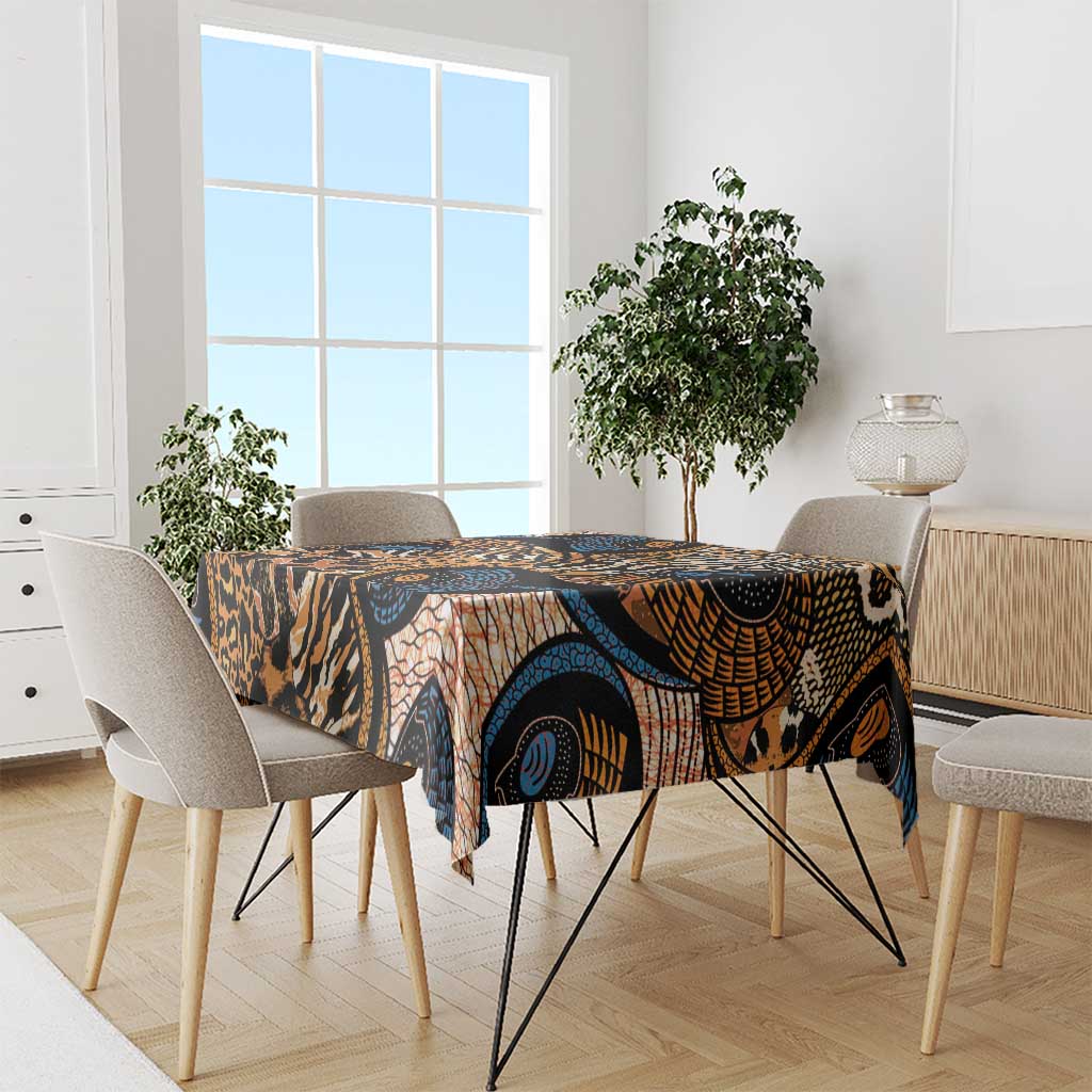 Printed tablecloth with black, orange, and blue animal-skin motifs draped on a dining table