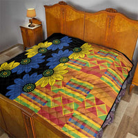 Black quilt covering a bed, with blue and yellow daisies over multicolor striped squares