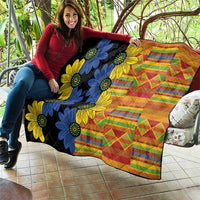 Black quilt draped on a sofa, showing blue and yellow floral shapes and colorful grid