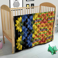 Black baby quilt on a crib with blue and yellow daisy flowers and multicolor geometric print