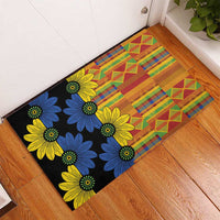 Black kitenge-style rubber doormat with floral corner and colorful geometric stripe pattern