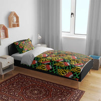 Kanga bedding set on bed with green, orange, yellow and black geometric leaf design
