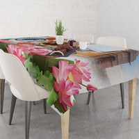 Tablecloth with pink lotus blossoms over green leaf design on dining table with chairs