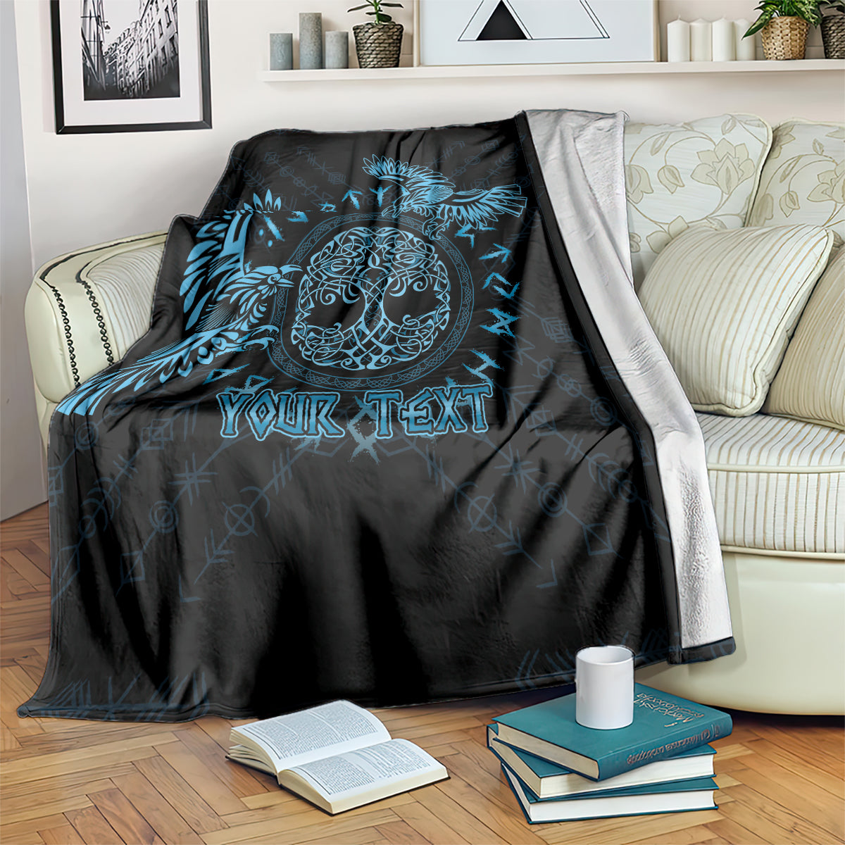 Black throw blanket with blue Celtic raven design and customizable text, on a sofa