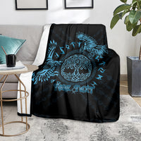Black throw blanket with blue Celtic raven and circular knot emblem, on a gray sofa