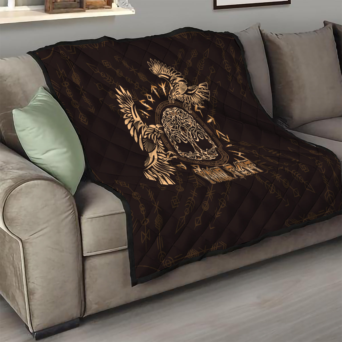 Black quilt throw with gold Celtic raven skull illustration and diamond quilting on a sofa.