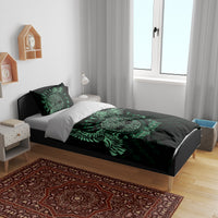 Black duvet cover with green Celtic raven motif and two matching pillowcases on a bed