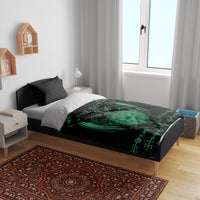 Black and green bedding set with dragon emblem and sword, shown on bed