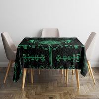Black tablecloth with green dagger-and-rune pattern, neatly covering dining table