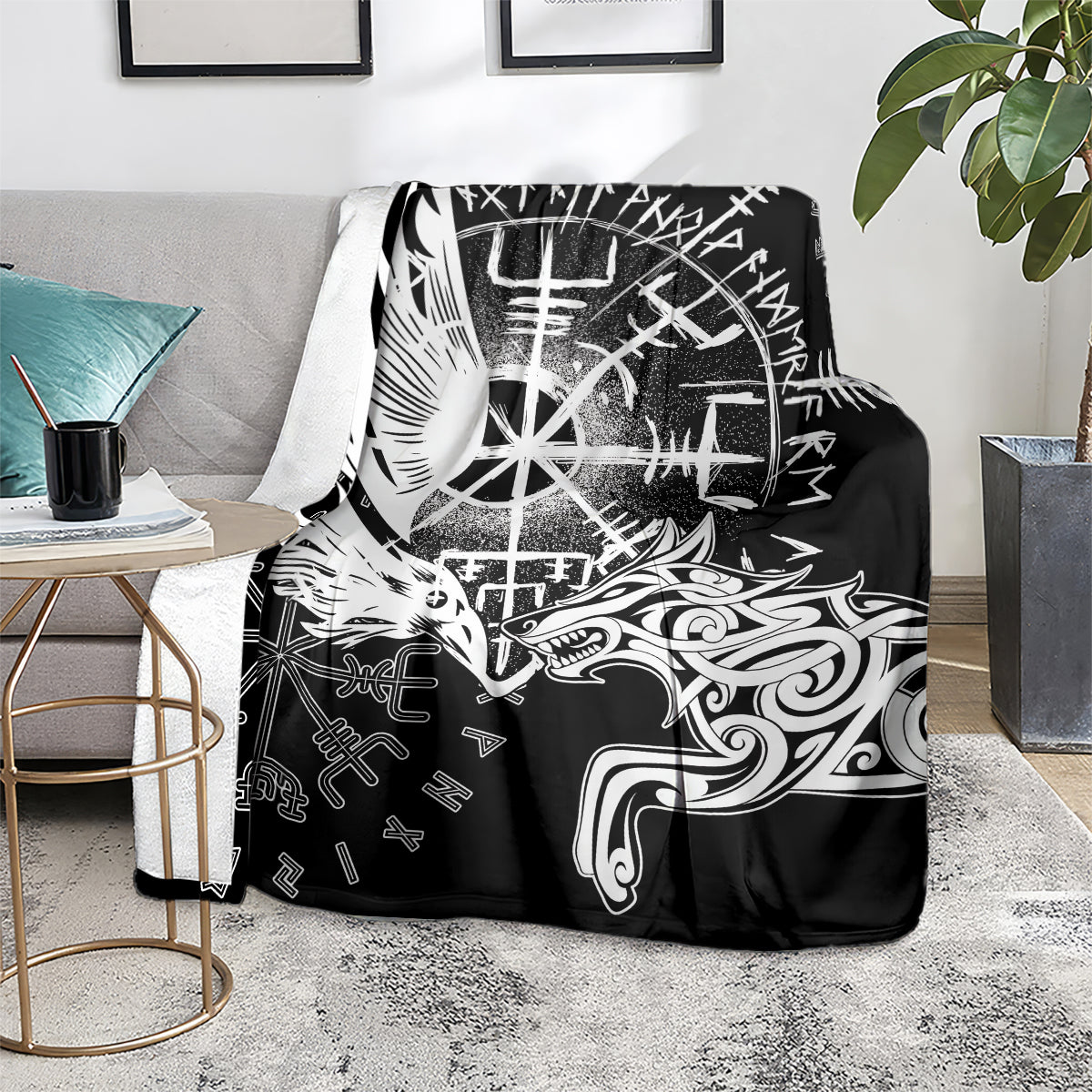 Black blanket with white raven and wolf artwork, laid on sofa