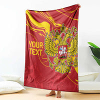 Red double-headed eagle blanket with gold crest and custom text, hanging over floor