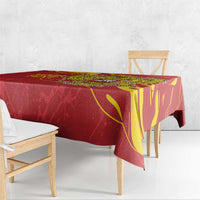 Red tablecloth draped over dining table with gold emblem and decorative borders