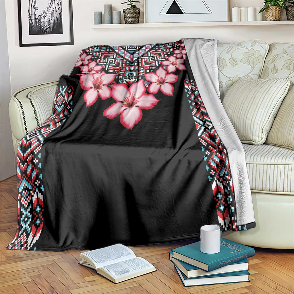 Black floral blanket with pink flowers and tribal geometric border, draped over sofa