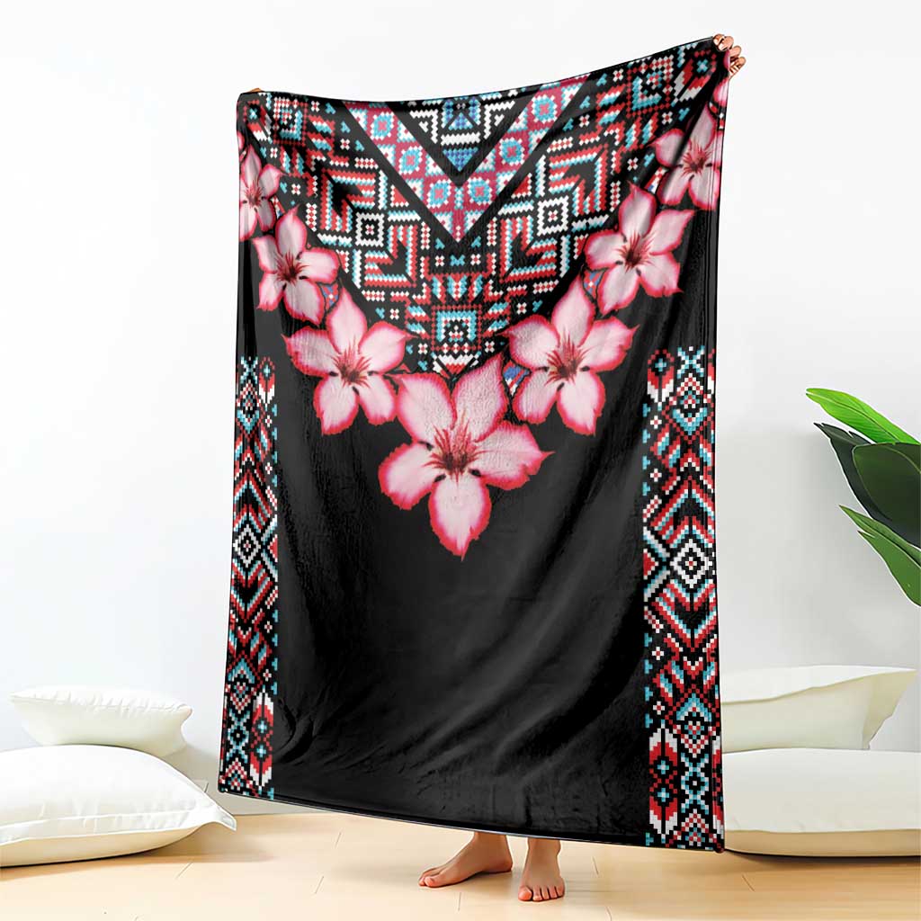 Black floral and tribal pattern blanket with pink flowers and geometric border, draped over surface