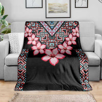 Black blanket with pink flower print and colorful tribal edging, spread over sofa