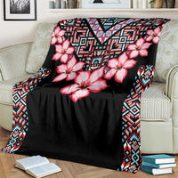 Black blanket with pink hibiscus flowers and tribal border, draped on sofa with books