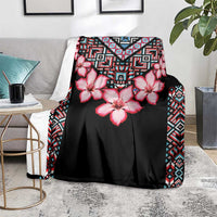 Black floral blanket with pink hibiscus and multicolor geometric border, on chair