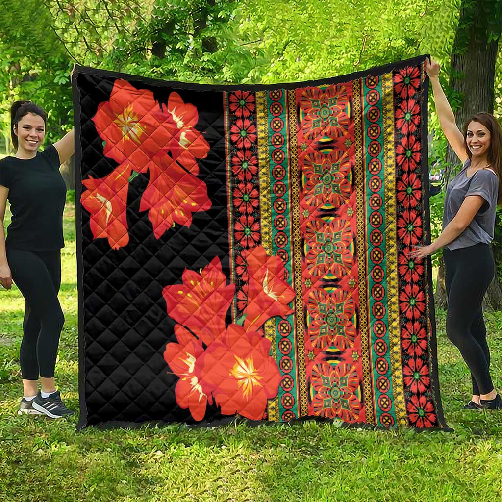 Black quilt with red-orange flower print and patterned multicolor strip border, spread wide