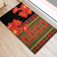 Black rubber doormat corner view with orange flowers and ornate red-green stripe border
