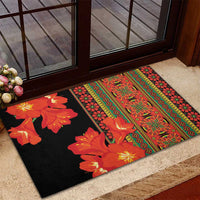 Black rubber doormat with orange floral panels and red-green patterned edge