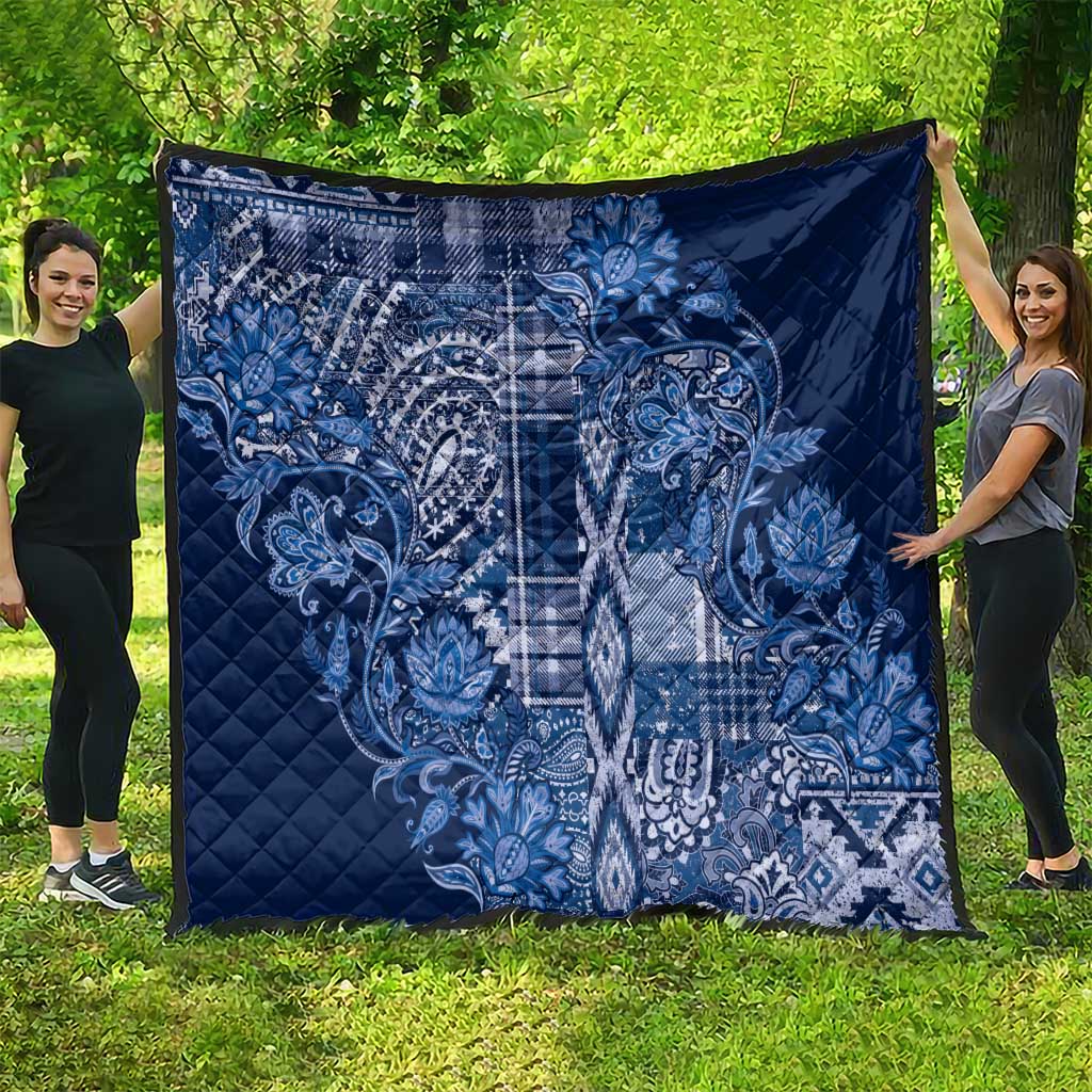 Blue diamond-quilted blanket with white paisley and plaid motif, laid out flat